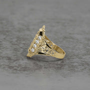 Side view of a two-tone gold San Judas ring with cubic zirconia on textured background.