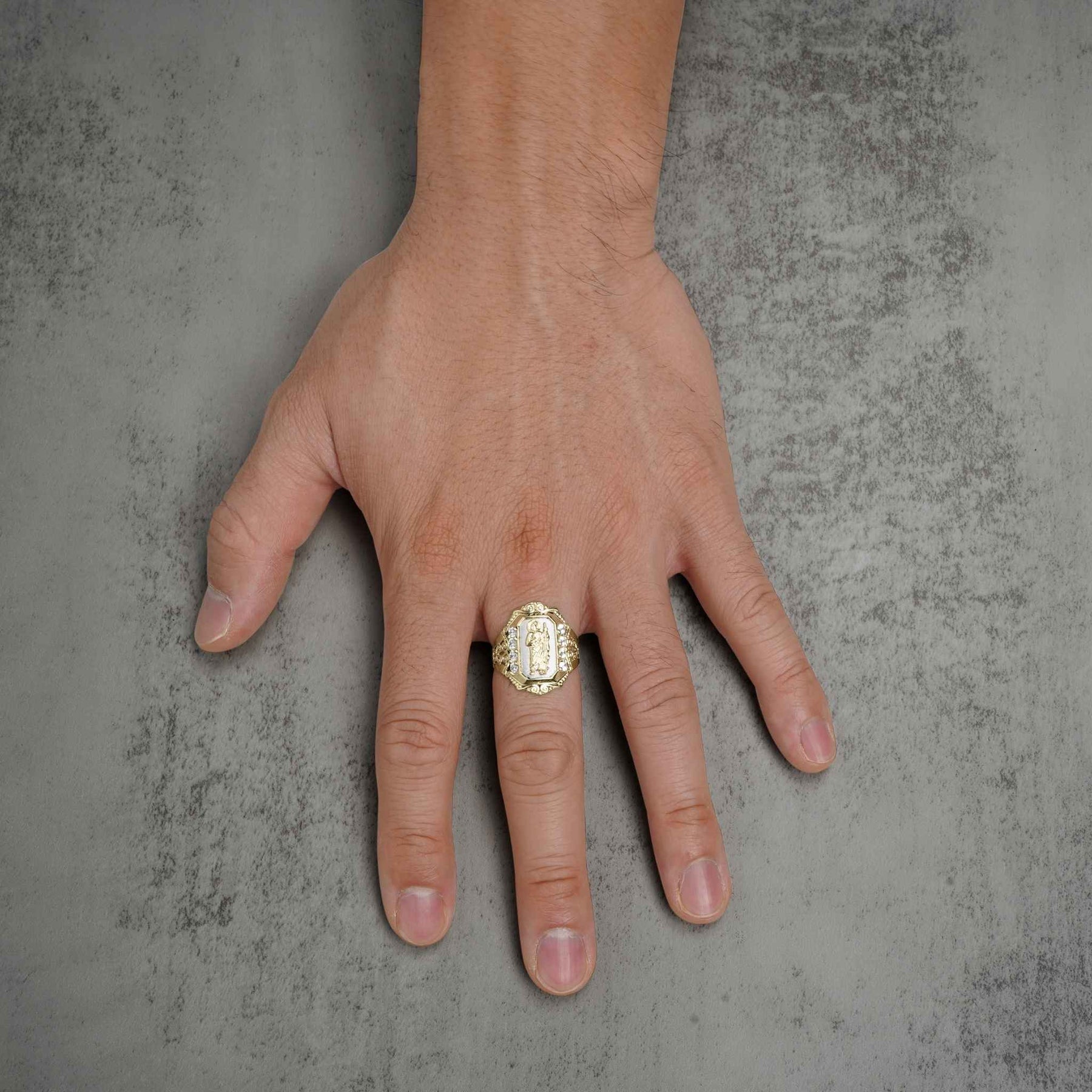 Top-down view of a hand wearing a two-tone gold San Judas royal ring.