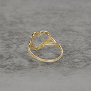 Side view of a 10k and 14k gold open-heart nugget ring on a textured background.