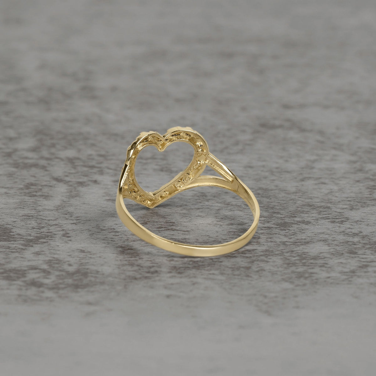 Side view of a 10k and 14k gold open-heart nugget ring on a textured background.