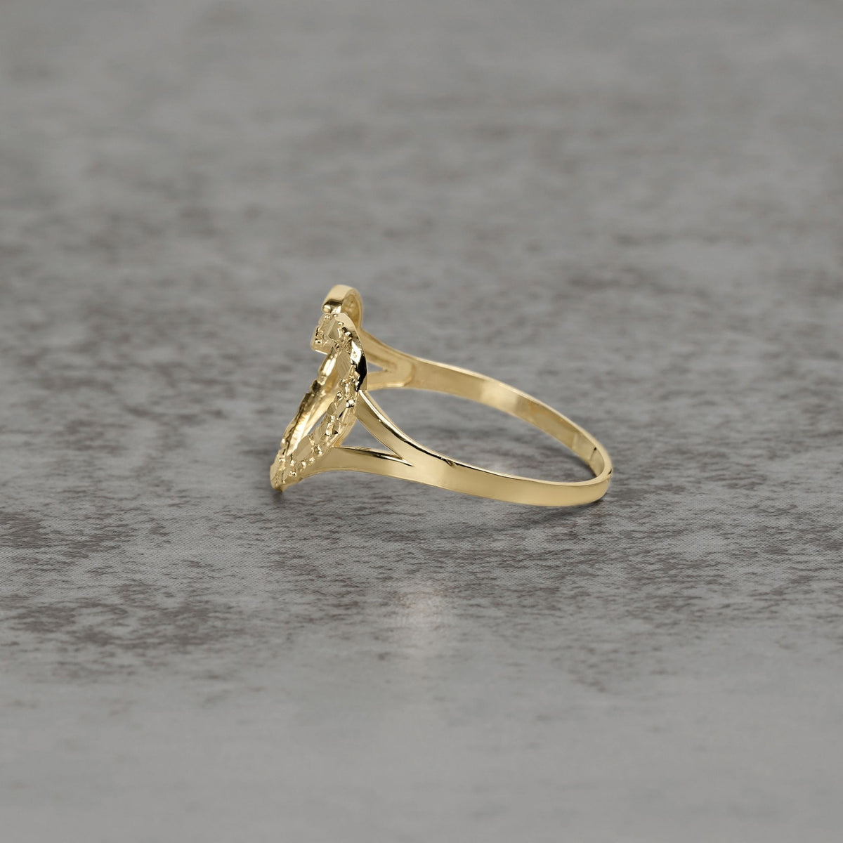 Side view of a 10k and 14k gold open-heart nugget ring on a textured background.