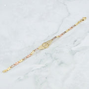Three-tone gold quinceañera leaf bracelet back view resting on white marble surface.