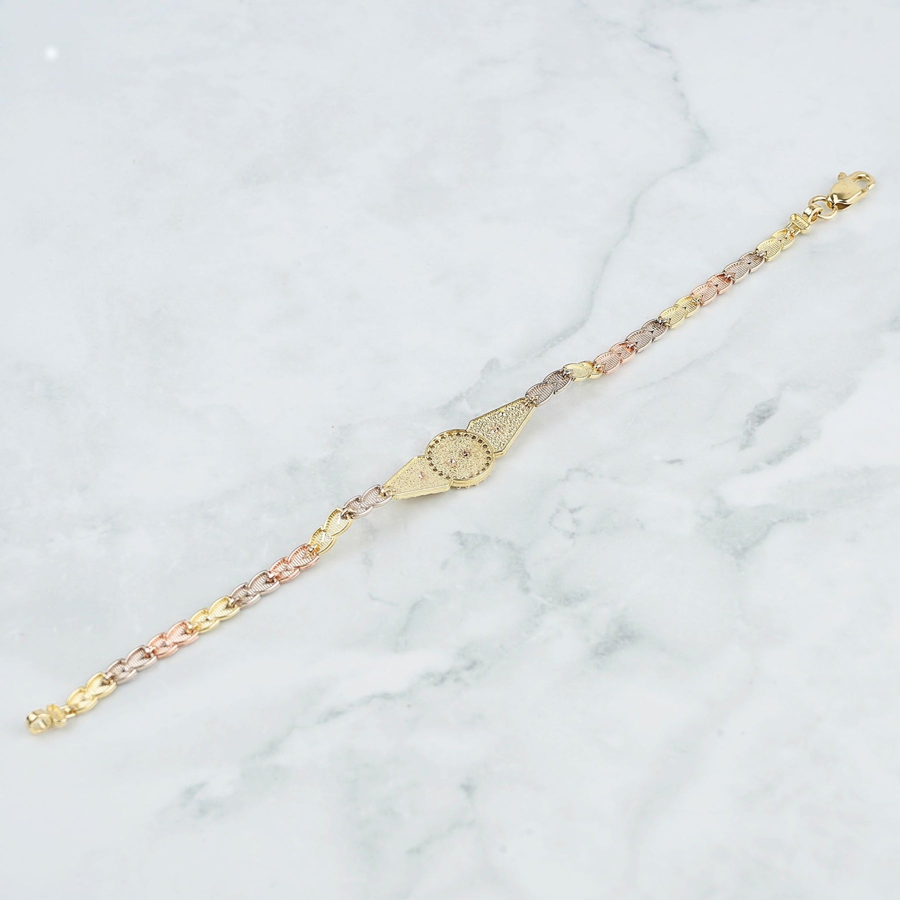 Three-tone gold quinceañera leaf bracelet back view resting on white marble surface.
