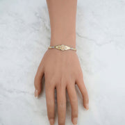 Lifestyle image of the tri-color gold Quinceañera leaf bracelet worn on a wrist.