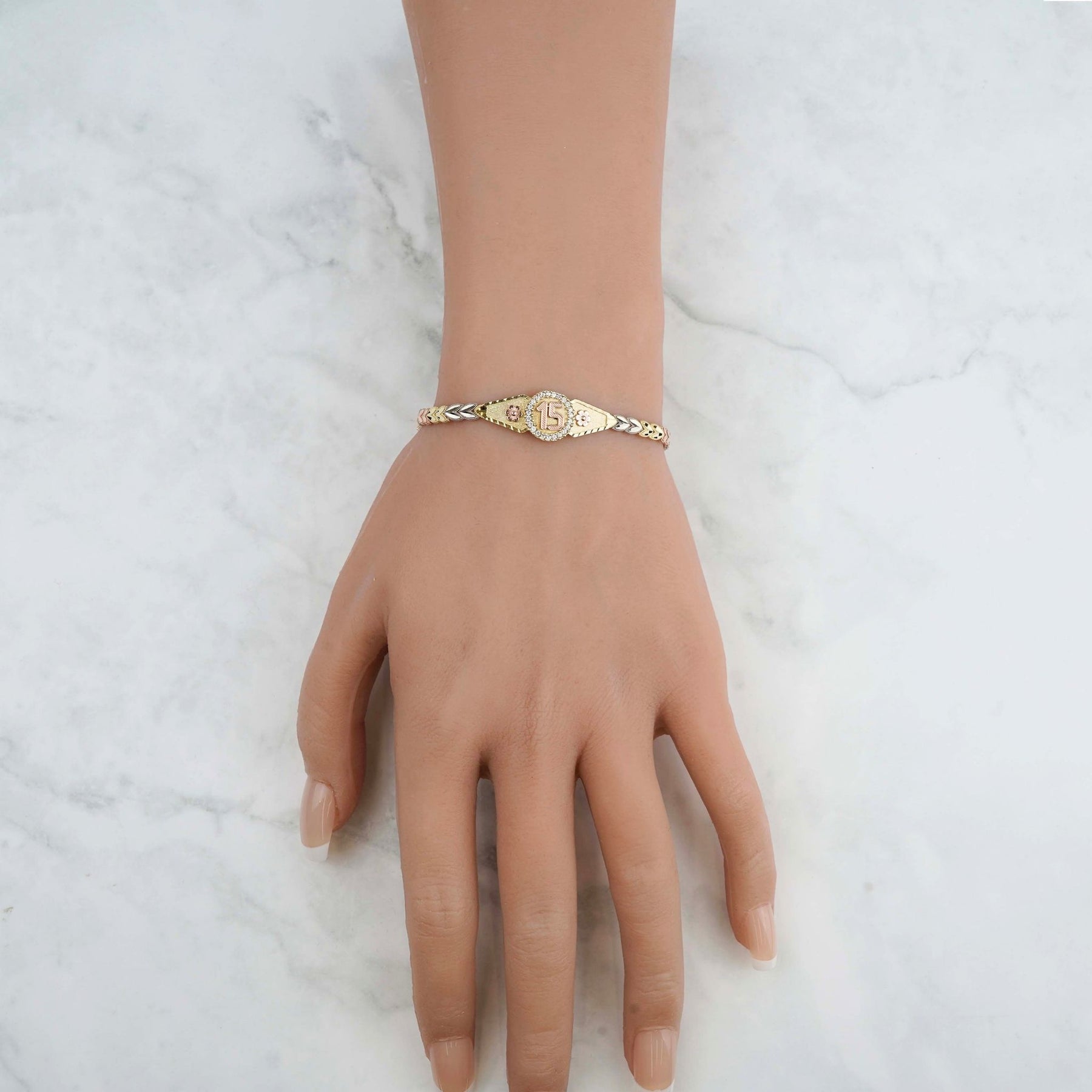 Lifestyle image of the tri-color gold Quinceañera leaf bracelet worn on a wrist.