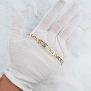 Tricolor gold 15 Años quinceañera leaf bracelet displayed on a white gloved hand.