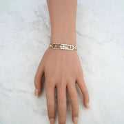 Top-down view of a tricolor gold "15 Años" leaf bracelet on a hand.