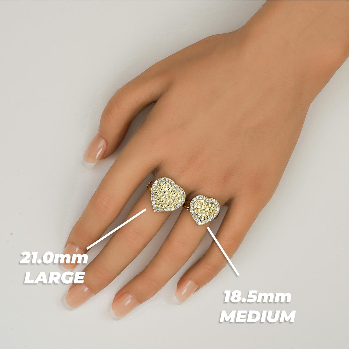 Size comparison of two gold heart-shaped nugget rings on a finger with millimeter labels.