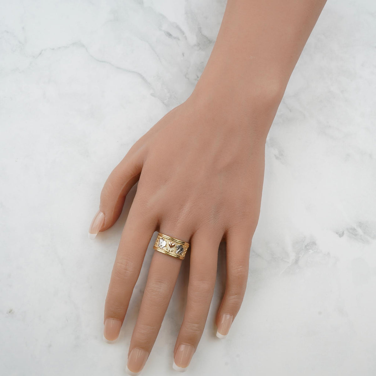 Hand wearing the tricolor gold lucky elephant ring against a marble background.