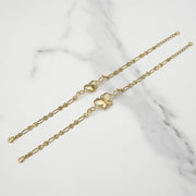 Two gold two-tone Virgin Mary Guadalupe butterfly bracelets laid diagonally on white marble