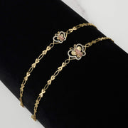 Two gold two-tone Virgin Mary butterfly bracelets on a black display surface.