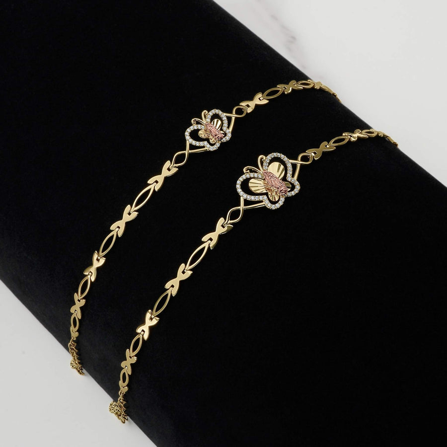 Two gold two-tone Virgin Mary butterfly bracelets on a black display surface.