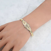Close-up of the tri-color gold quinceañera leaf bracelet showing the central "15" medallion.