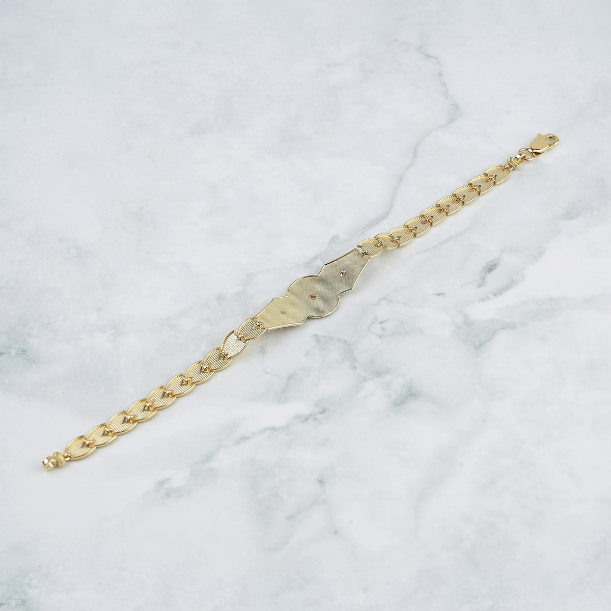 Back view of a gold Quinceañera "15 Años" leaf link bracelet on marble.
