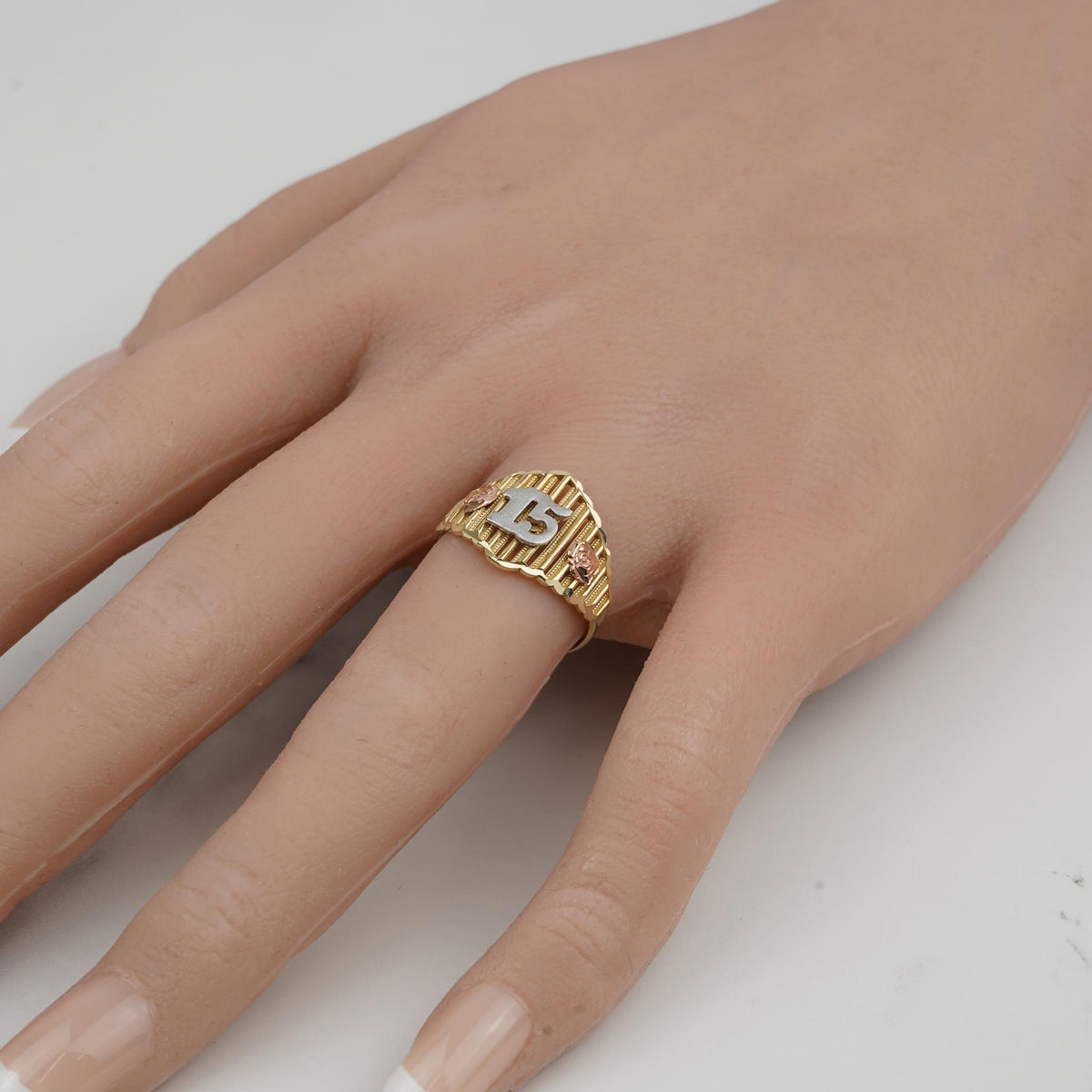 Gold 15 Quinceañera ring with rose floral accents worn on ring finger.