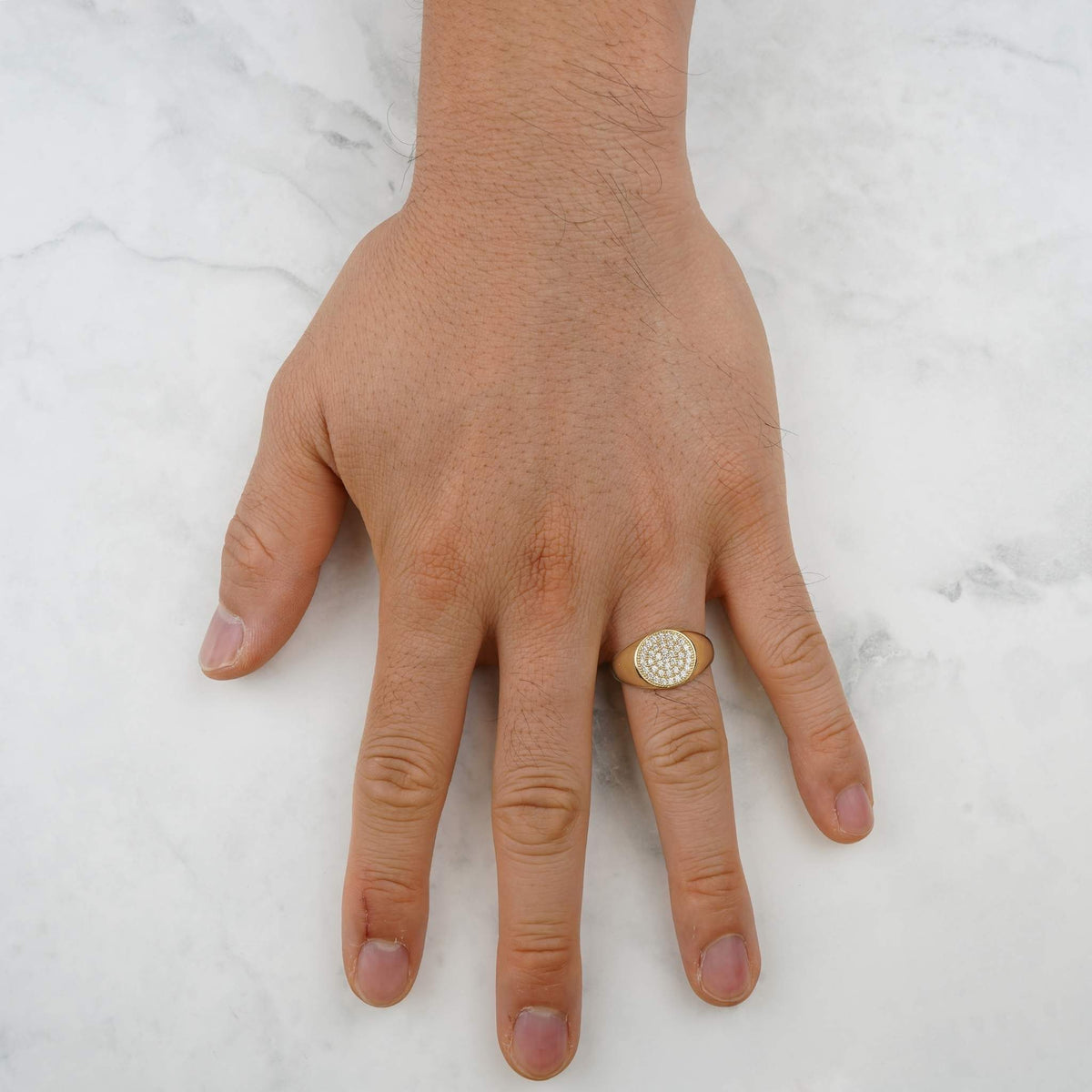 Man wearing a round gold signet ring with paved CZ stones on his hand.