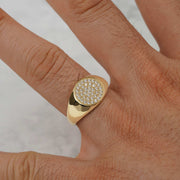 Close-up of a gold round CZ signet ring worn on a hand