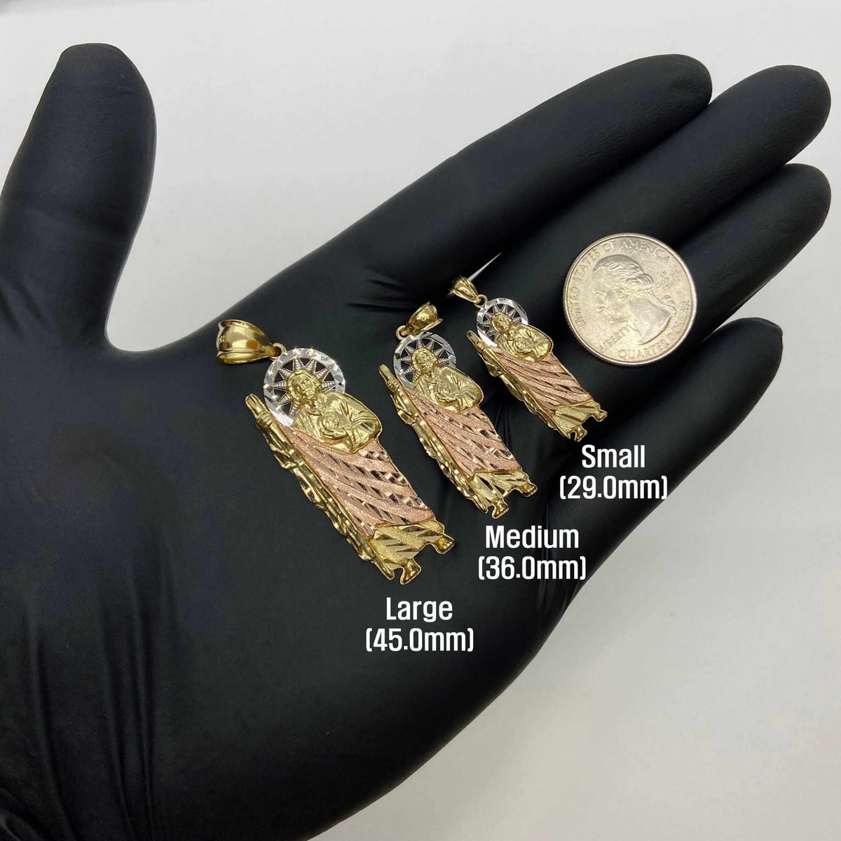 Three tri-color gold San Judas pendants in Small, Medium, Large on black gloved hand.