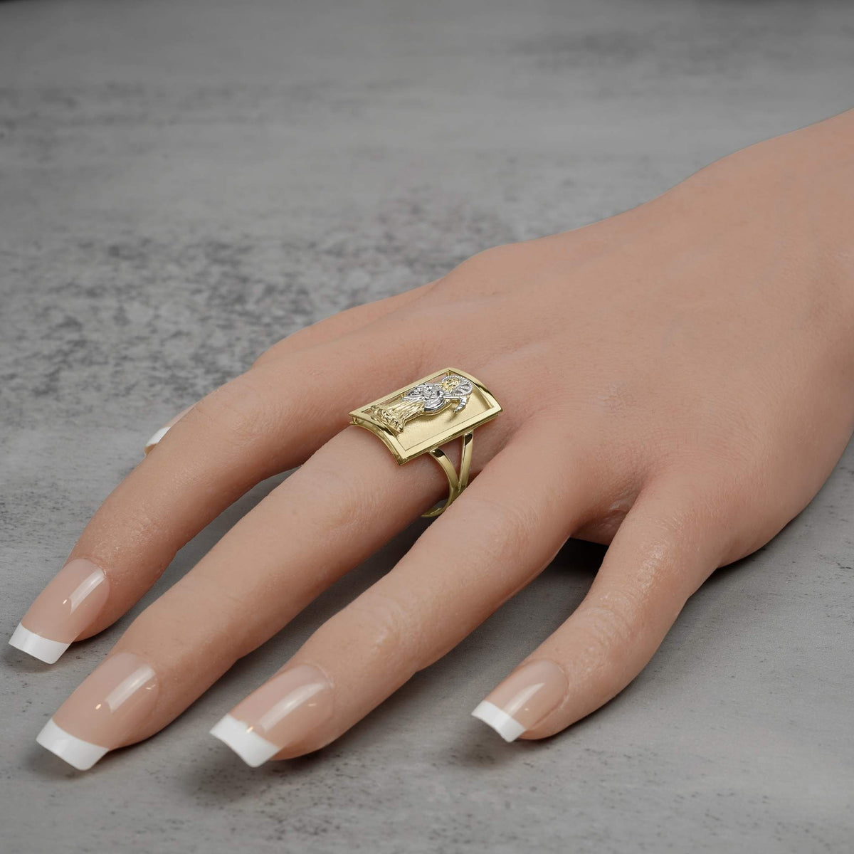 Bold yellow gold rectangular statement ring featuring a white gold death reaper design worn casually.