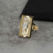 Men's two-tone gold rectangular Grim Reaper religious signet ring displayed on gray stone background.