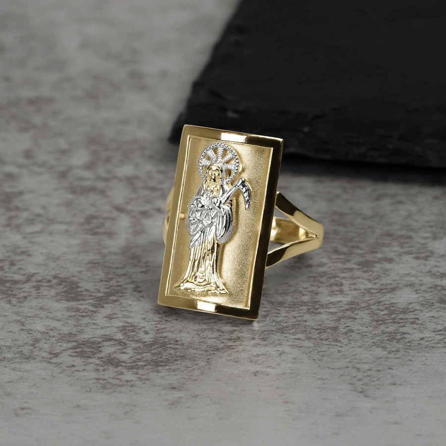 Men's two-tone gold rectangular Grim Reaper religious signet ring displayed on gray stone background.