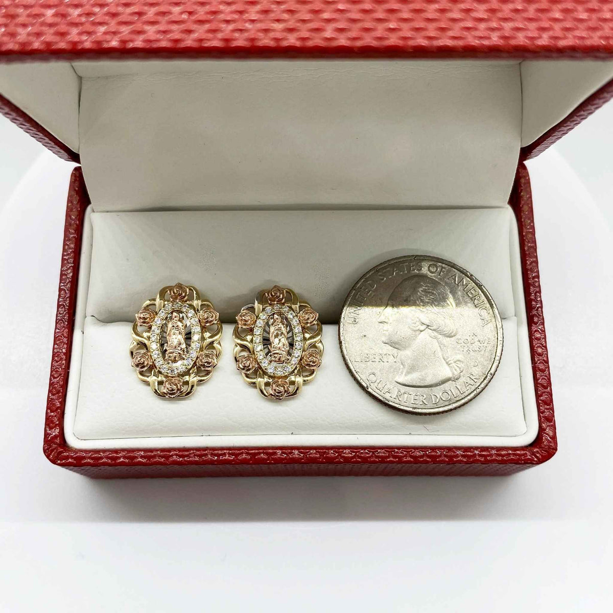 Virgin Mary oval stud earrings next to a U.S. quarter for size comparison.