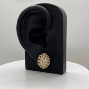 Tri-color gold Virgin Mary oval stud earring displayed on a black ear-shaped jewelry stand.
