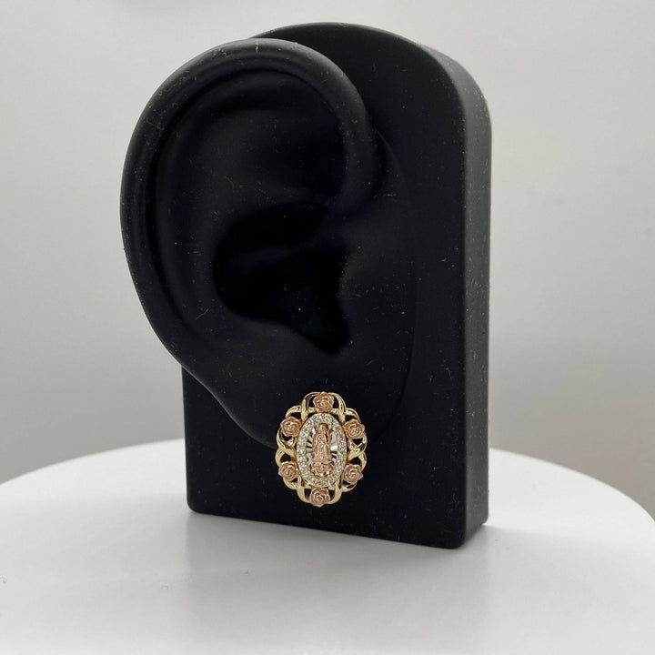 Tri-color gold Virgin Mary oval stud earring displayed on a black ear-shaped jewelry stand.