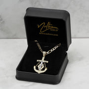 Gold anchor crucifix pendant necklace presented inside a black velvet display box on marble
