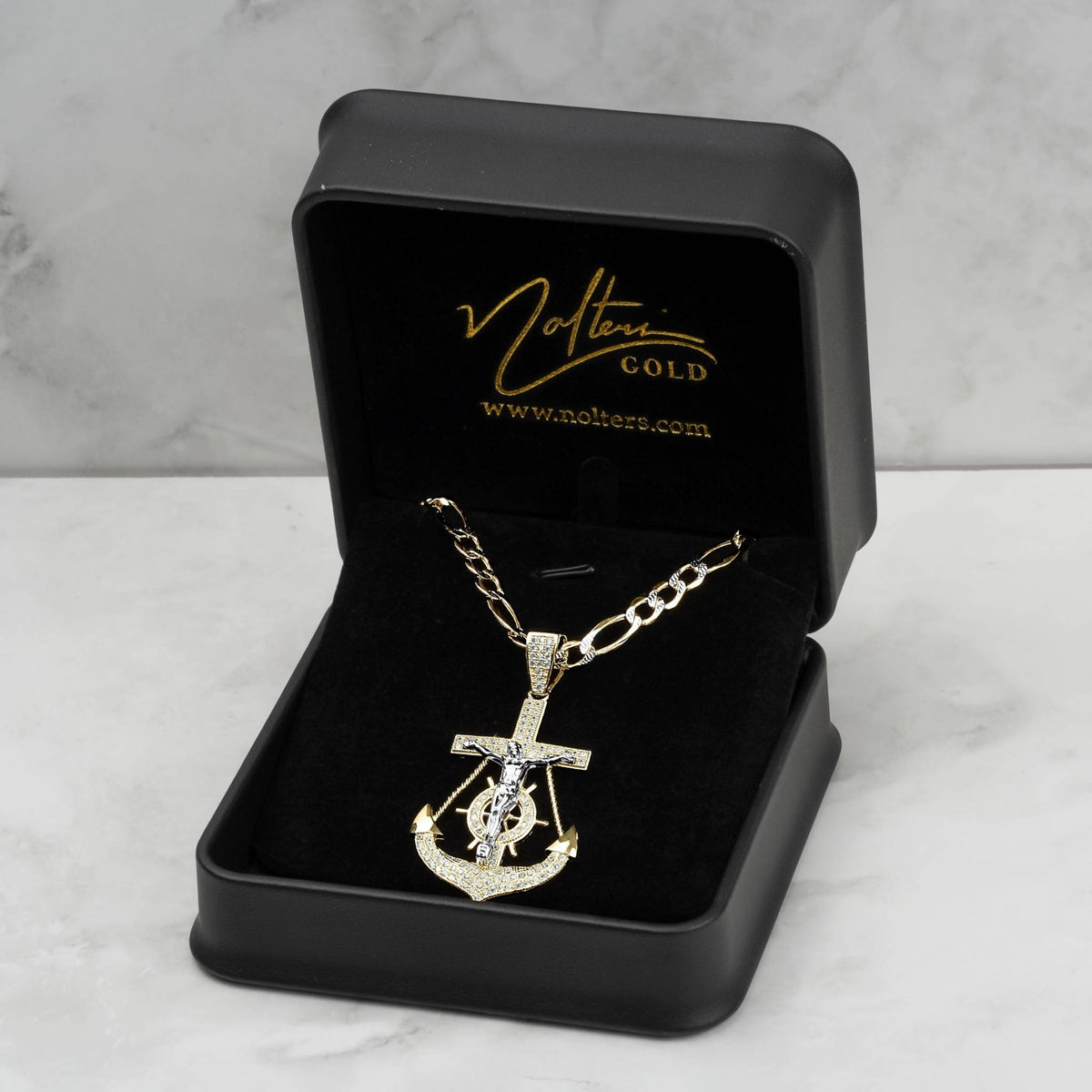 Gold anchor crucifix pendant necklace presented inside a black velvet display box on marble