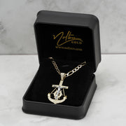 Gold anchor and crucifix pendant in an open black velvet gift box.