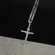 White gold tubular INRI crucifix necklace on a chain against a two-tone background.