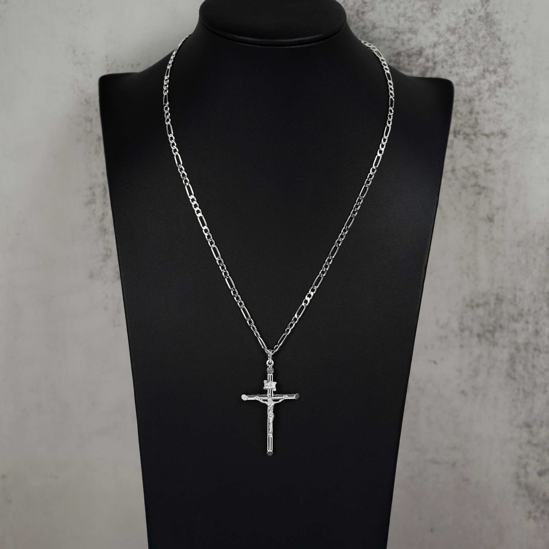 Classic 10k white gold tubular crucifix pendant and chain resting on a black display mannequin.
