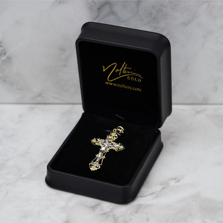 Ornate two-tone gold crucifix pendant displayed in a black Nolters jewelry box.