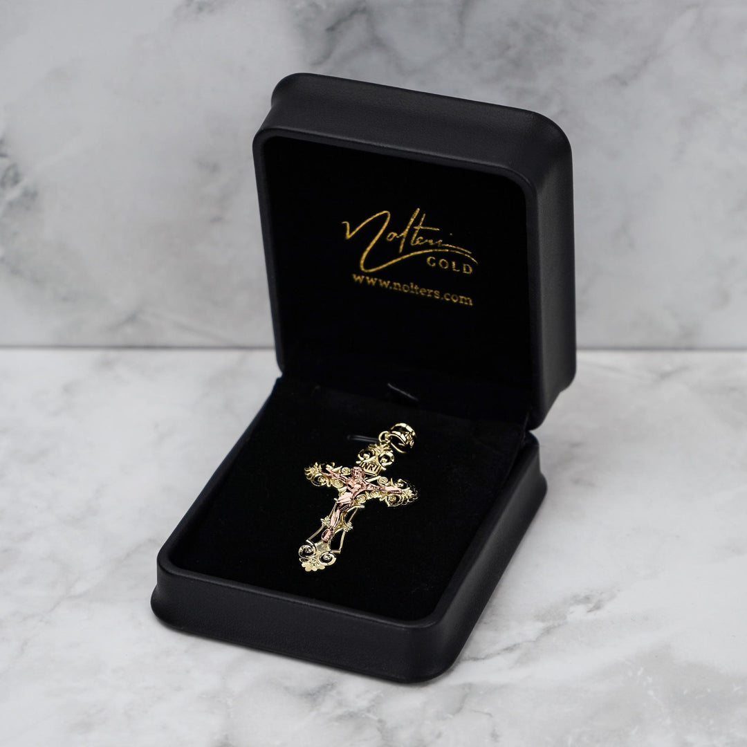 Religious INRI crucifix pendant in gold presented in a branded jewelry box on marble.