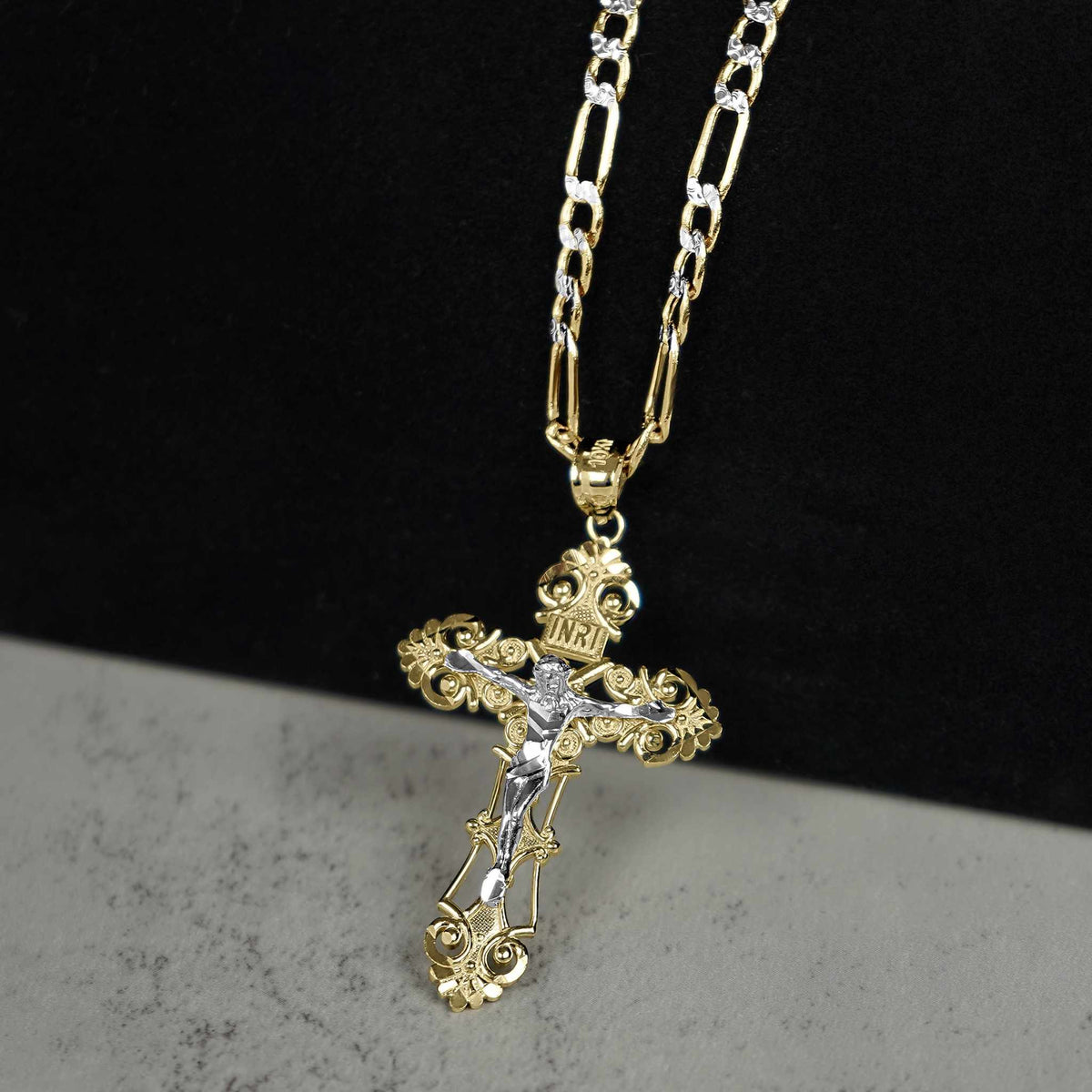 Two-tone gold and white gold INRI crucifix pendant on gold Figaro chain.