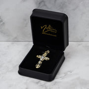 Gold crucifix pendant displayed inside an open black jewelry box with gold branding.