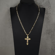A gold chain necklace with a cross pendant displayed on a black mannequin bust against a textured gray background.