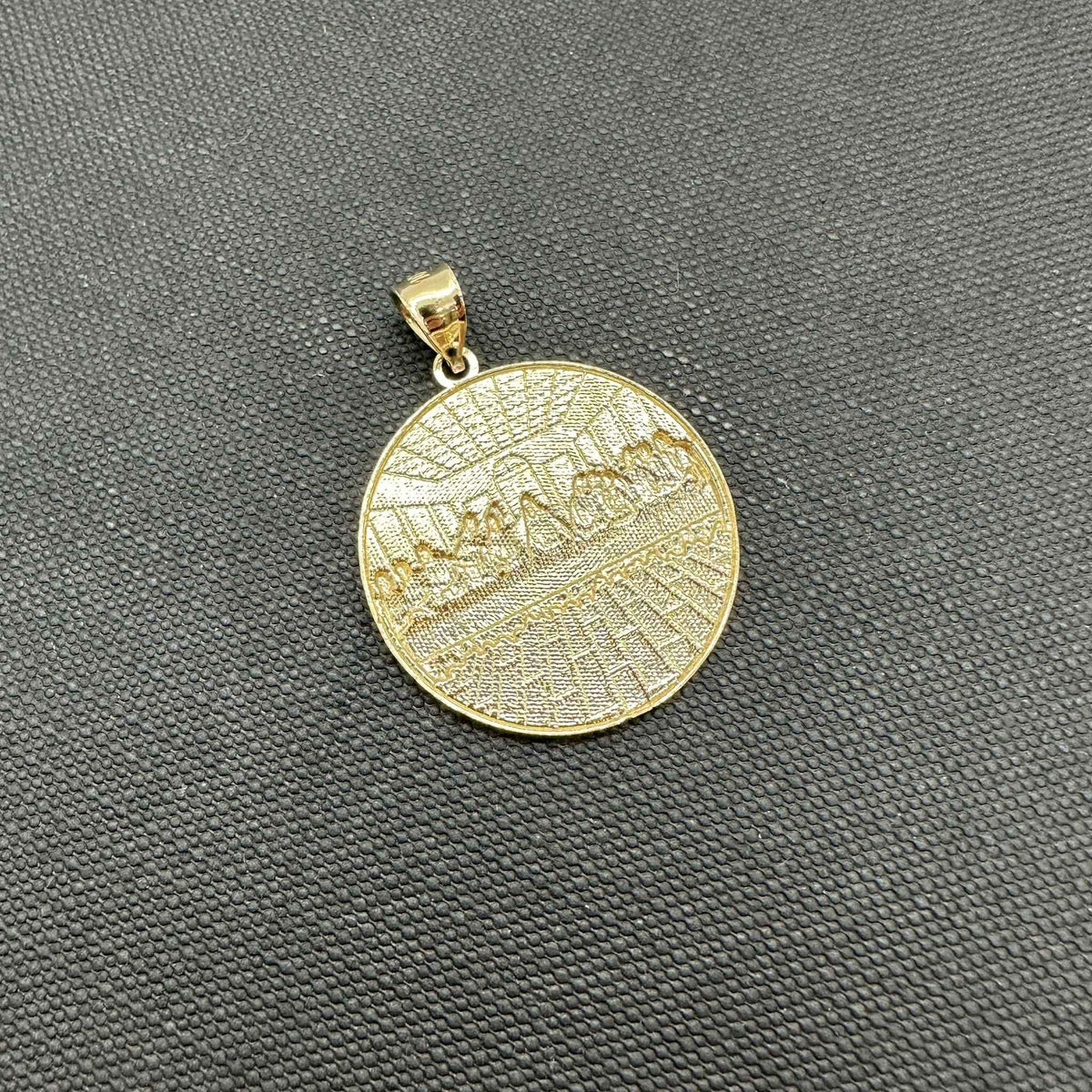 Back view of round gold Last Supper pendant featuring textured sunburst pattern.