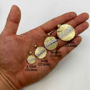 Size comparison of four round gold Last Supper pendants held in a palm.