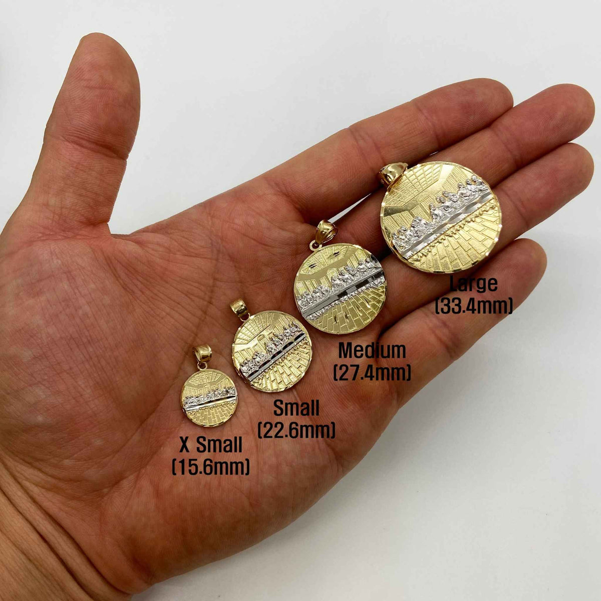 Size comparison of four round gold Last Supper pendants held in a palm.
