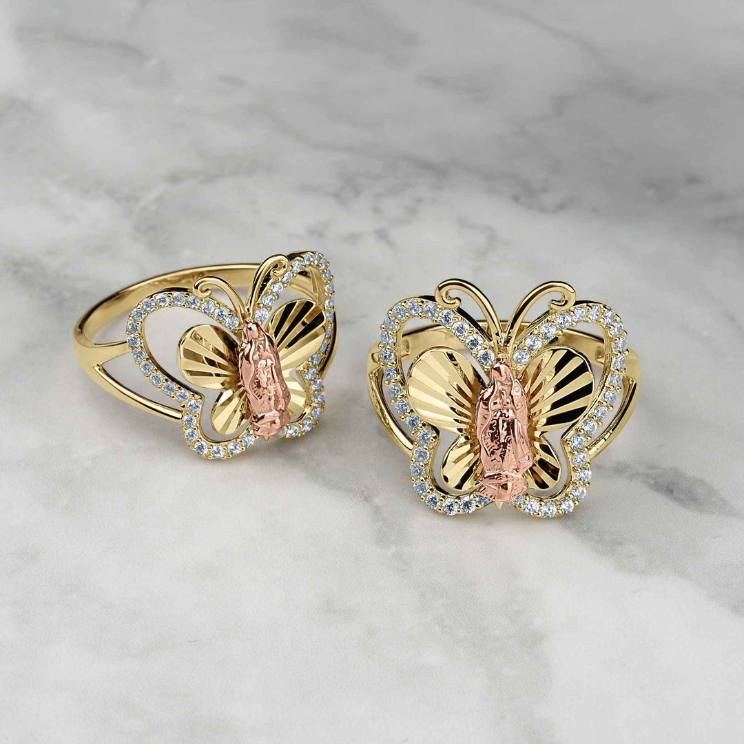 Two gold Virgin Mary Guadalupe butterfly rings with CZ stones on marble.
