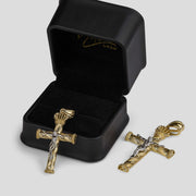 Two two-tone gold crucifix pendants displayed with an open black presentation box.