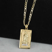 Rectangular two-tone gold Guadalupe pendant hanging on a gold chain against a dark background.