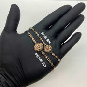 Black-gloved hand displaying Small and Medium size tri-color gold Virgin Mary bracelets.