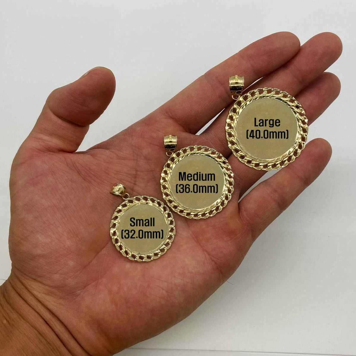 Open hand displaying small, medium, and large gold Cuban-link picture pendants.