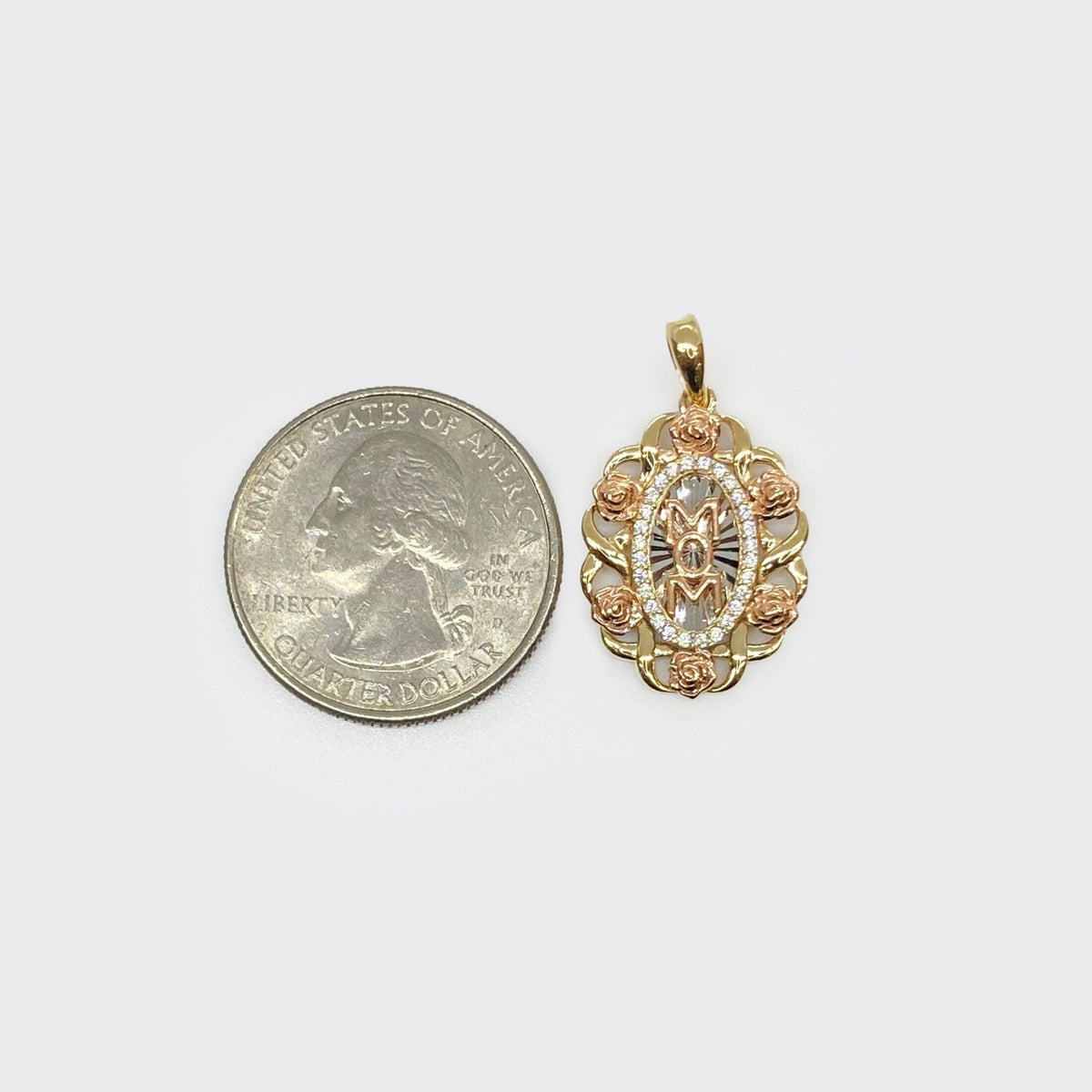 Tri-color gold floral 'MOM' pendant displayed next to a US quarter for scale.