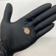 Gloved hand holding a tri-color gold oval 'MOM' rose pendant charm.