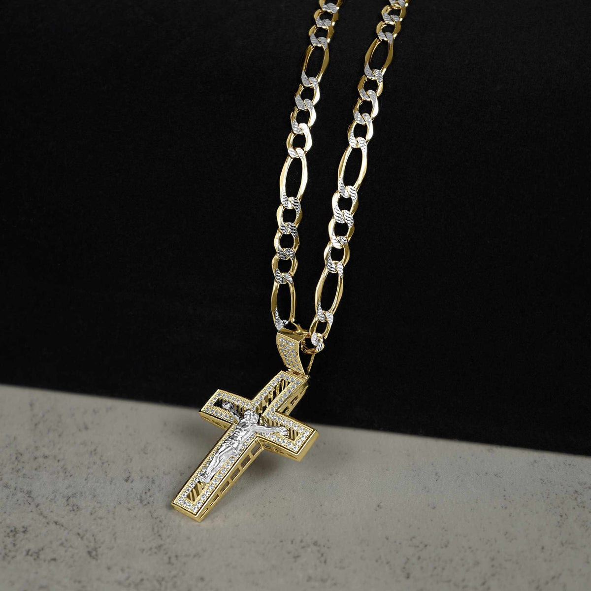 Yellow and white gold crucifix pendant with sparkling cubic zirconia, hanging from a Figaro chain.