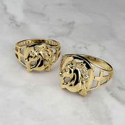 Two yellow gold horseshoe rings with a detailed horse head center on marble.